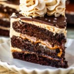 Slice of caramel Guinness chocolate cake with layers of chocolate cake, vanilla buttercream, and caramel filling, topped with chocolate ganache and salted caramel buttercream swirls.