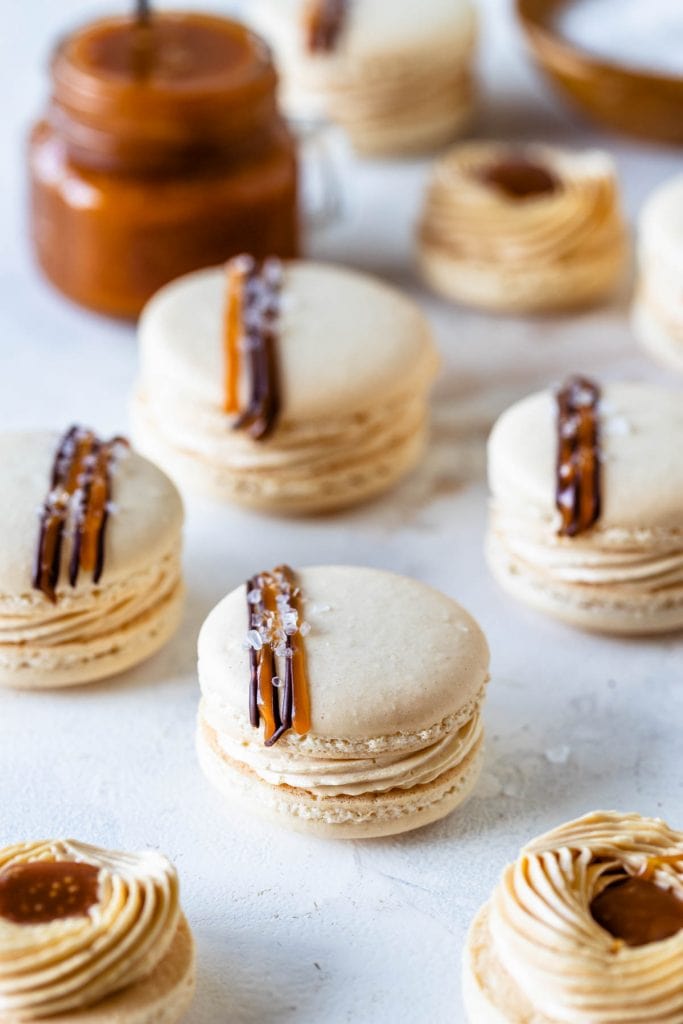 Salted Caramel Macarons filled with buttercream and topped with a drizzle of salted caramel and chocolate