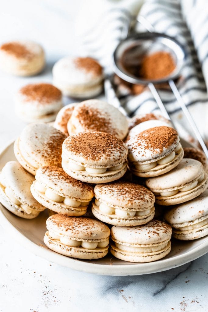 Tiramisu macaron filled with mascarpone frosting, dusted with cocoa powder in a plate