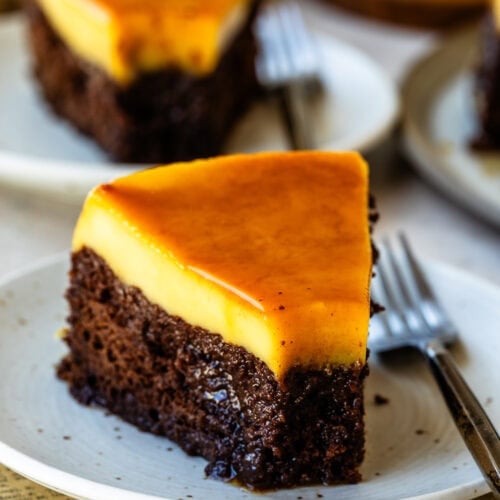 A slice of chocoflan featuring a smooth, glossy caramel flan layer sitting on top of a rich, moist chocolate cake base.