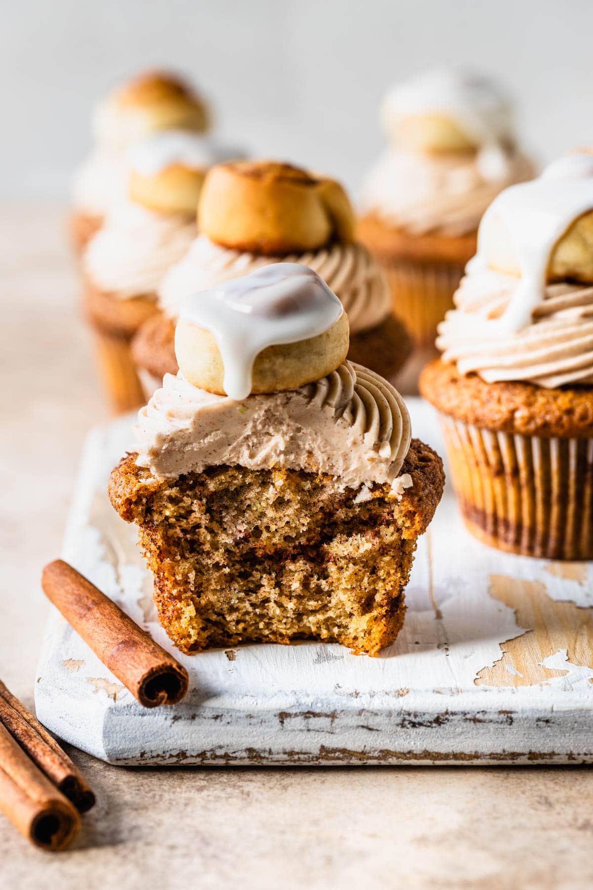 cinnamon roll cupcake sliced in half, topped with a glazed cinnamon roll.