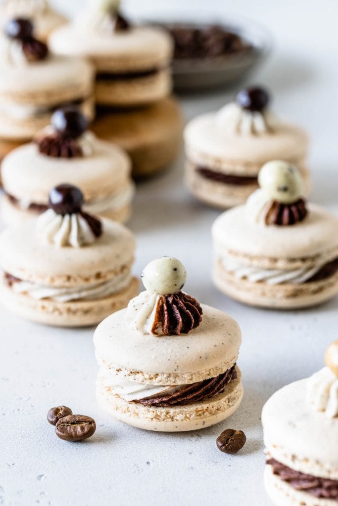 coffee macarons filled with a swirled frosting and topped with chocolate covered espresso bean.