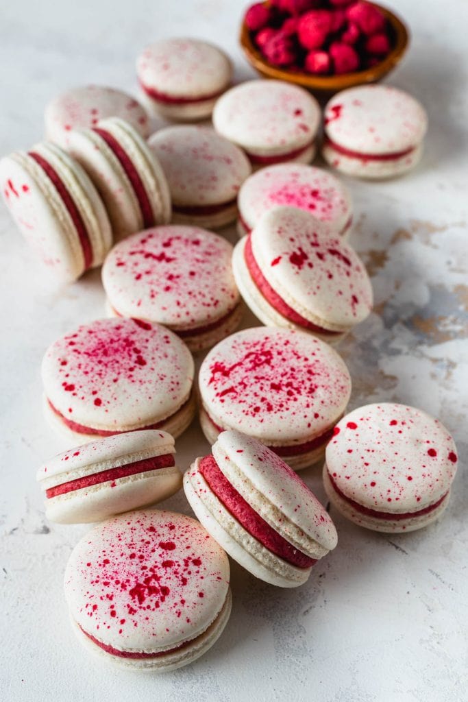Vegan Raspberry Macarons with a speckled pink shell, filled with pink frosting.