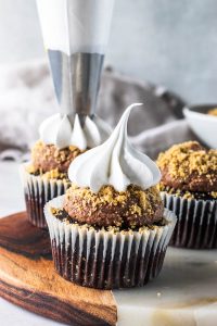 piping vegan marshmallow frosting on top of cupcakes