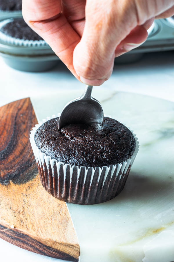 removing the center of a chocolate cupcake with a spoon