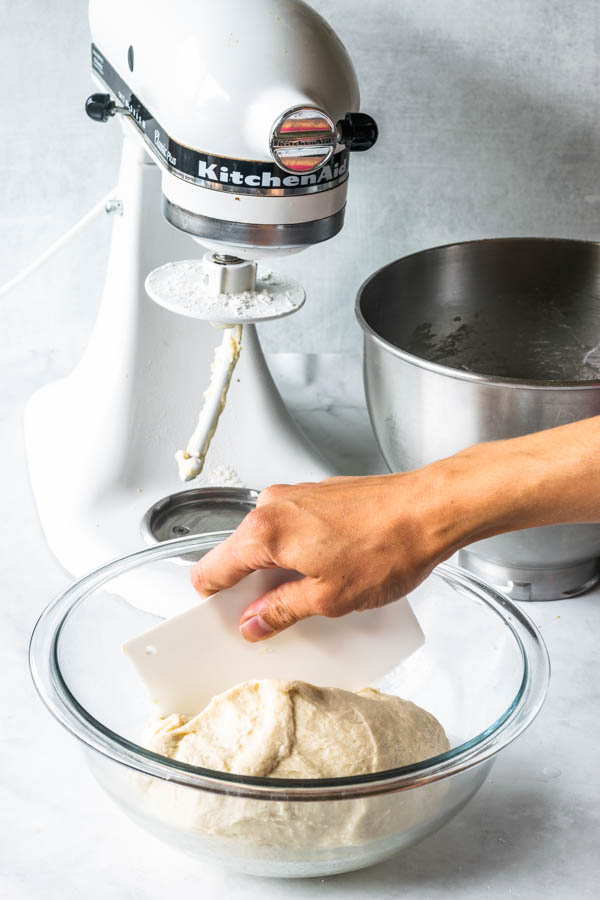 vegan donut dough being placed in a lightly oiled bowl