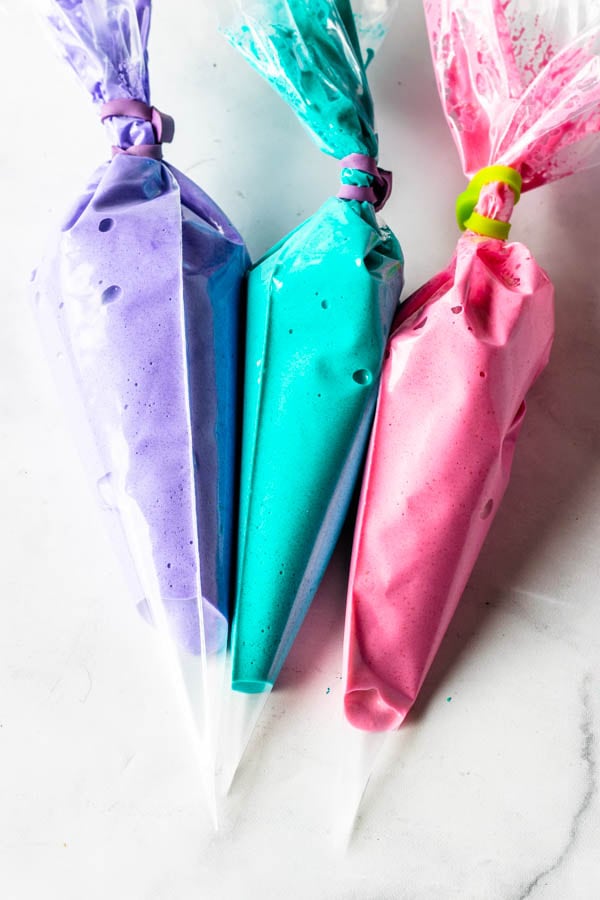 3 piping bags with 3 different macaron batter colors: purple, teal and pink