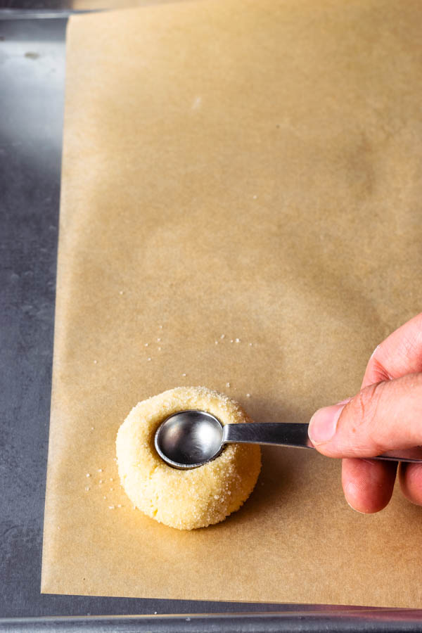 using a teaspoon to make indentation on cookie dough to make thumbprint cookie