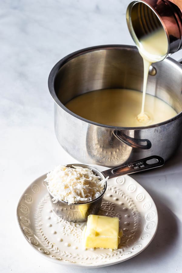 ingredients to make coconut fudge: coconut flakes, butter, and condensed milk