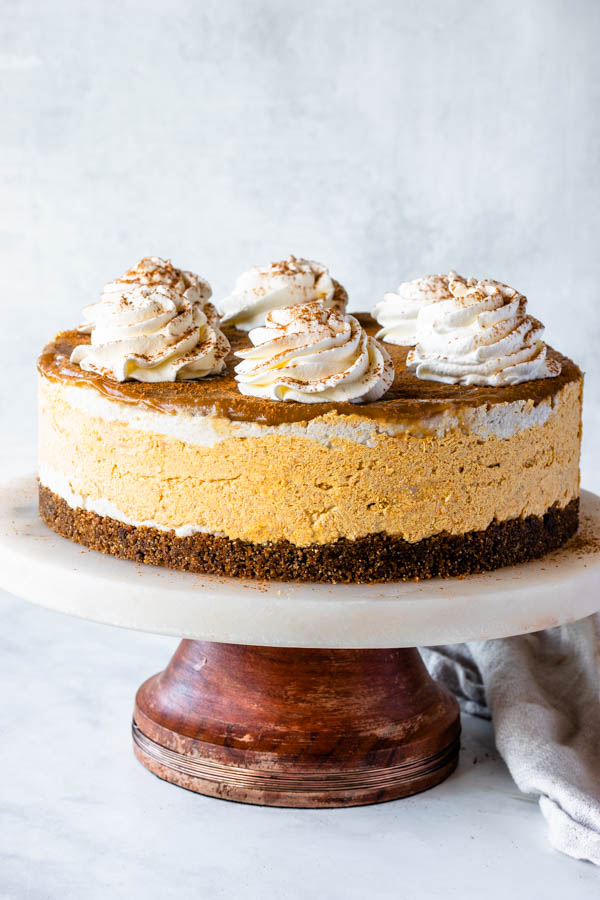vegan paleo pumpkin cheesecake with coconut whipped cream and caramel sauce on top