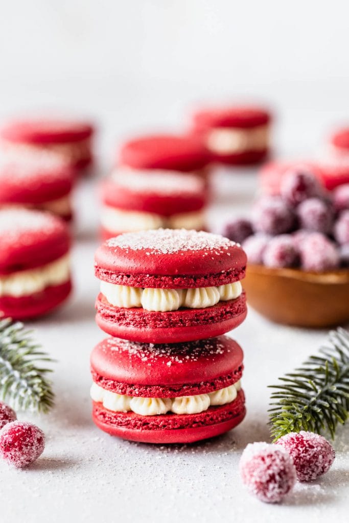 2 red macarons stacked, filled with cranberry sauce and orange buttercream.