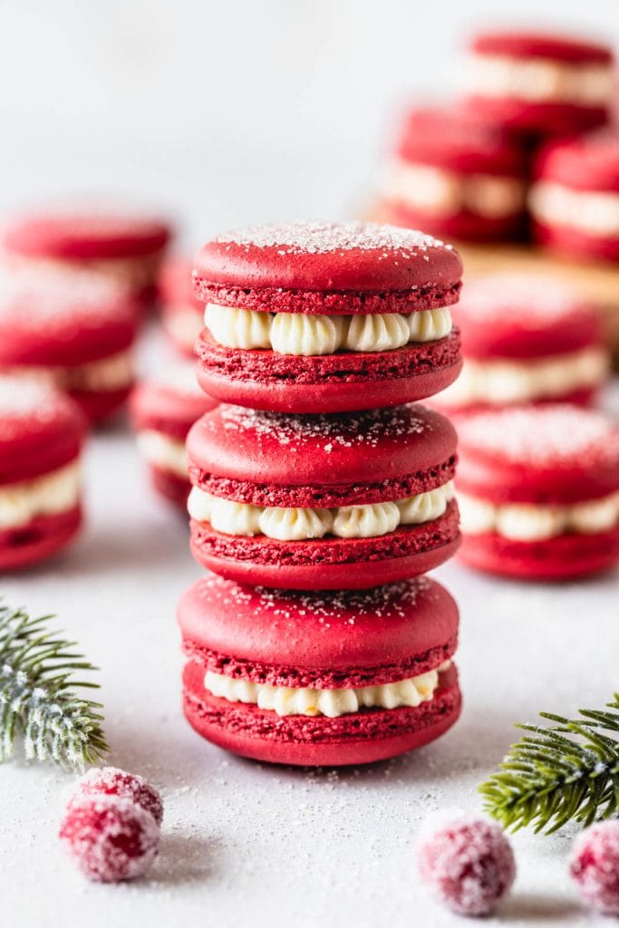 3 red macarons stacked, filled with cranberry sauce and orange buttercream.