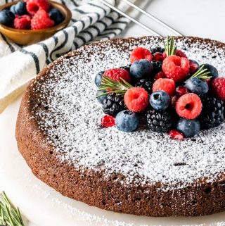 flourless Olive Oil Chocolate Cake dusted with powdered sugar and topped with fresh berries