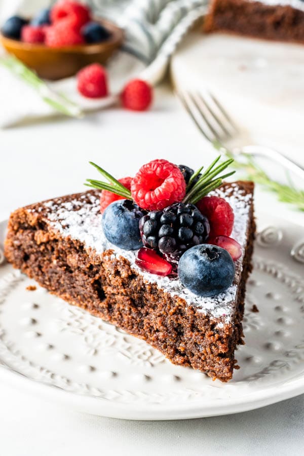 slice of flourless Olive Oil Chocolate Cake dusted with powdered sugar and topped with fresh berries