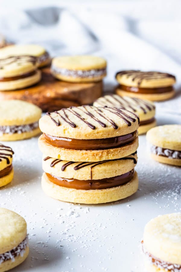 Alfajor Cookies filled with dulce de leche drizzled with melted chocolate