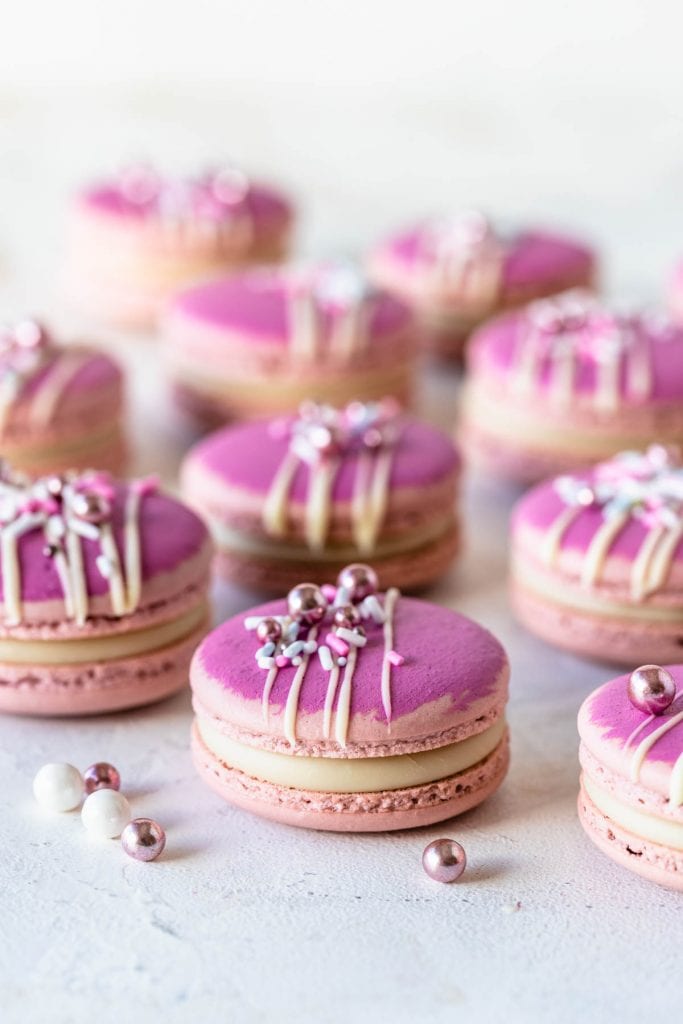 pink macarons topped with a drizzle of white chocolate and sprinkles.