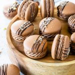 Nutella Macarons with chocolate drizzled on top and chopped hazelnuts