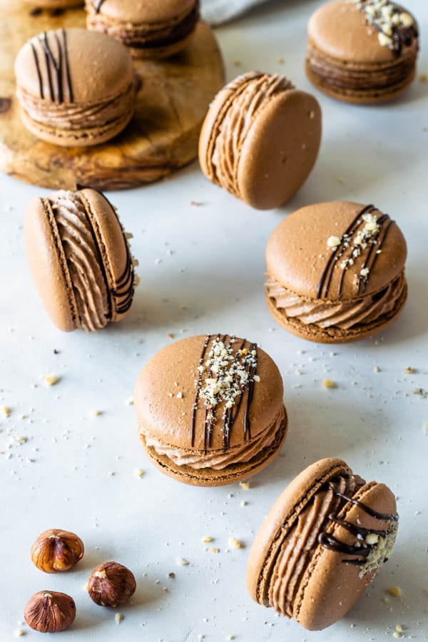 Nutella Macarons with chocolate drizzled on top and chopped hazelnuts