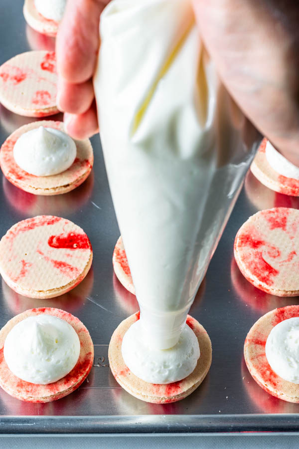 piping peppermint buttercream on top of macarons