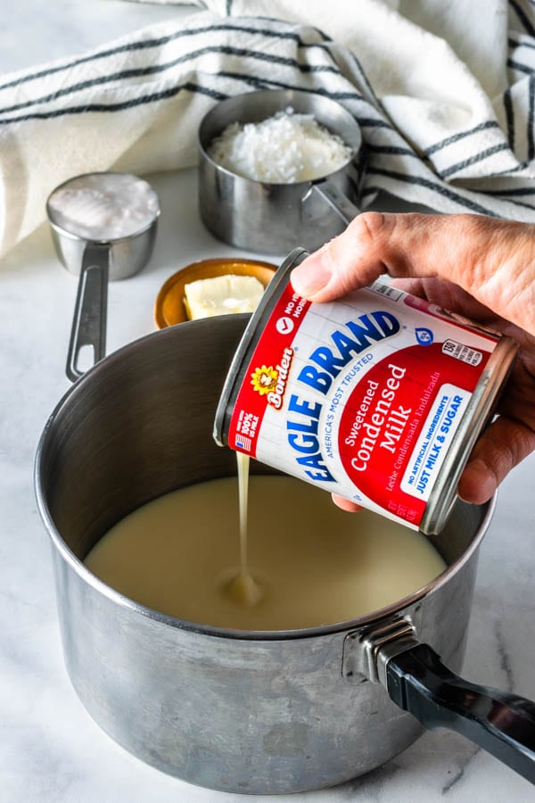 pouring condensed milk in a small saucepan 