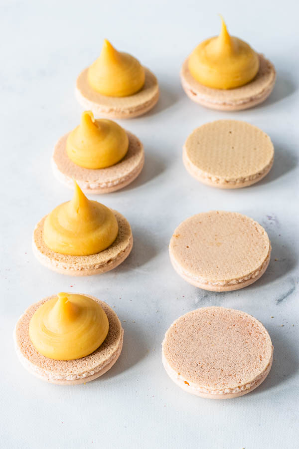 piping caramelized white chocolate on macarons