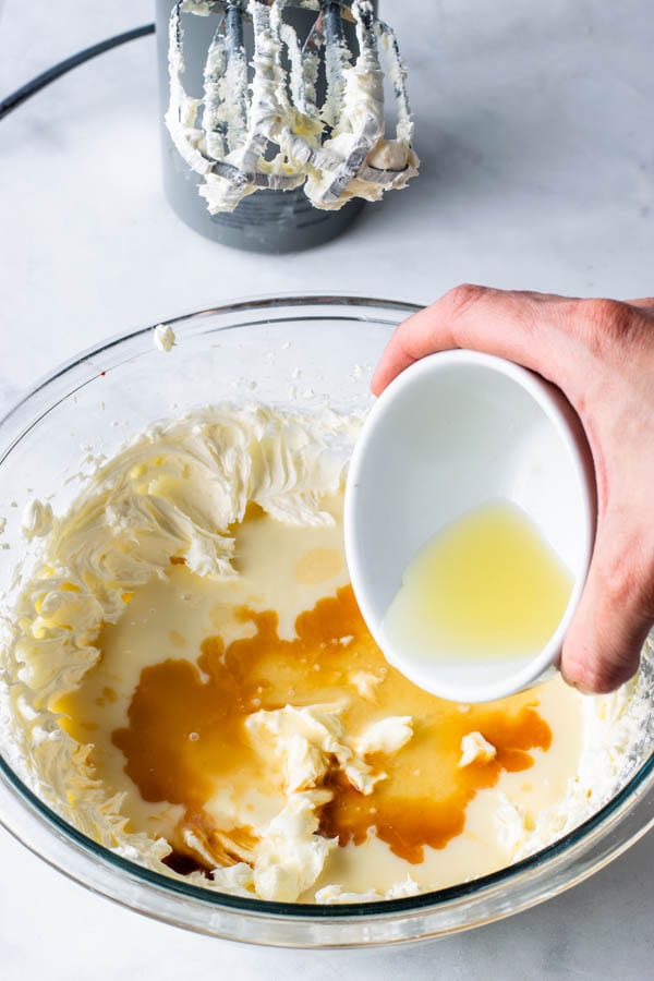 adding lemon juice and vanilla extract to cheesecake