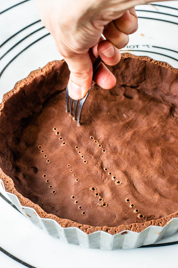 poking the bottom of a chocolate tart dough with a fork