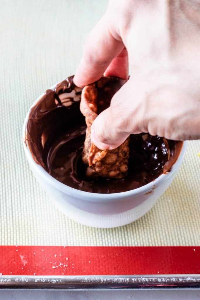 dipping cannoli in melted chocolate