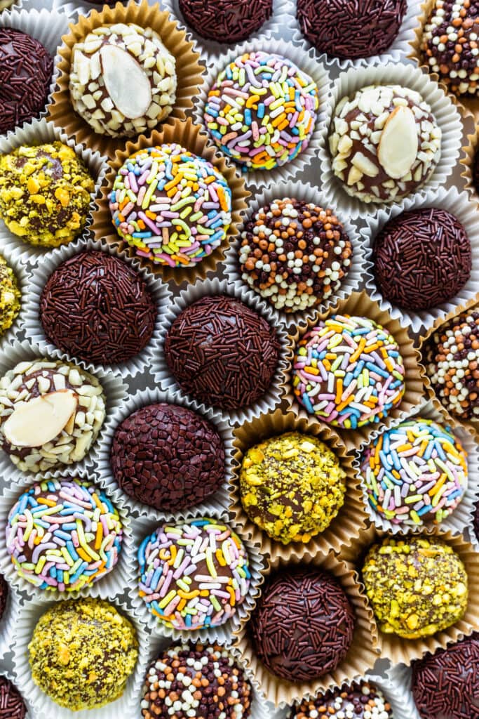 brigadeiros coated in sprinkles, chopped pistachios, chopped almonds.