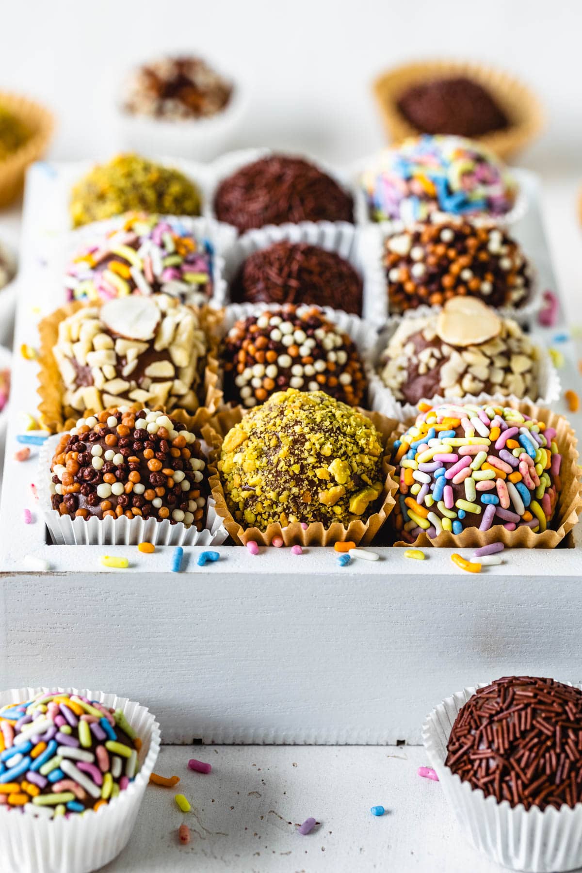 brigadeiros coated in sprinkles, chopped pistachios, chopped almonds.