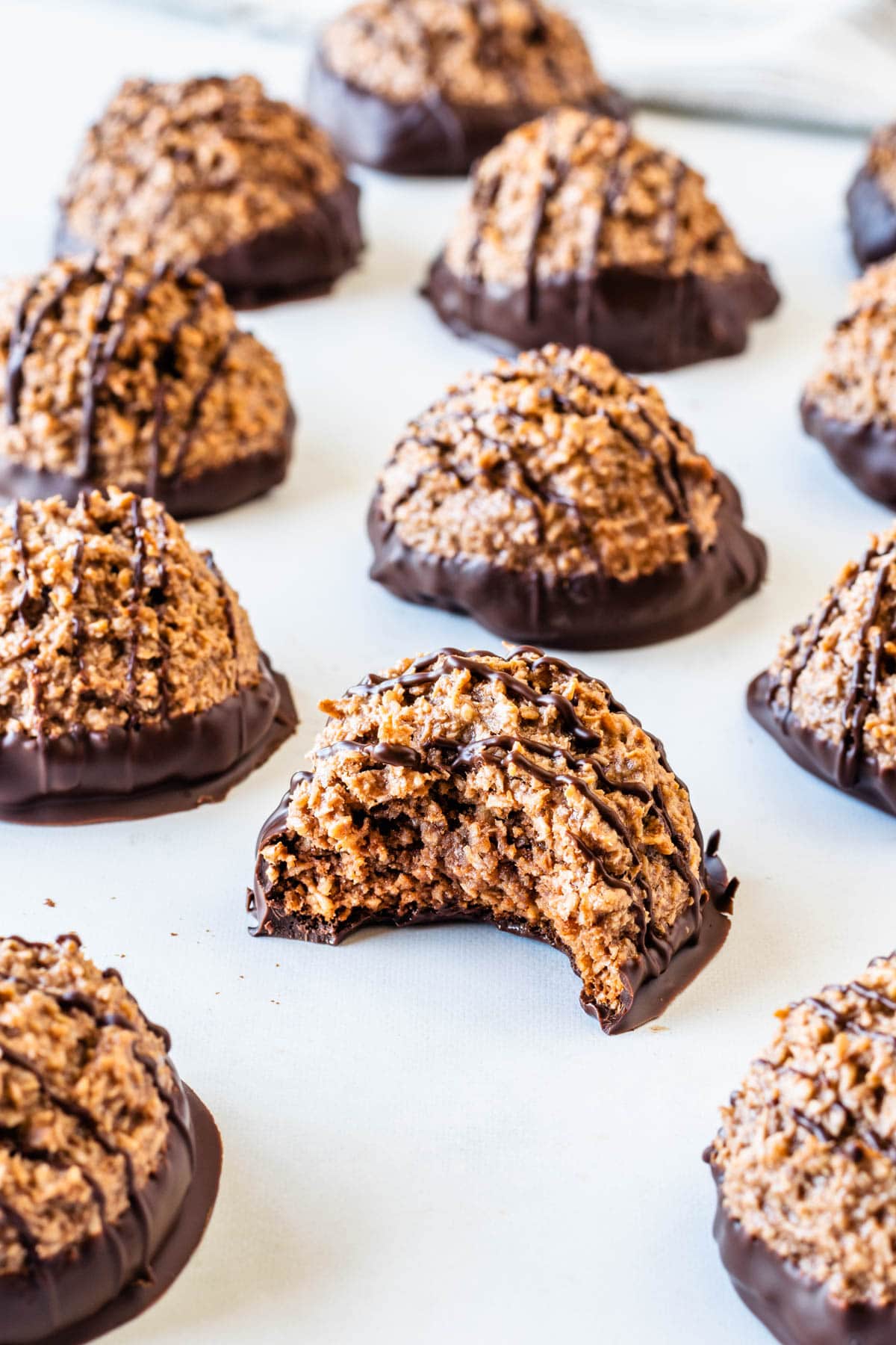 Chocolate coconut macaroon with a bite taken out, showing the soft chewy coconut center and chocolate-dipped bottom.