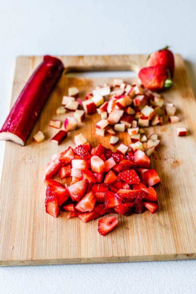 chopped strawberries and chopped rhubarb on a wooden board