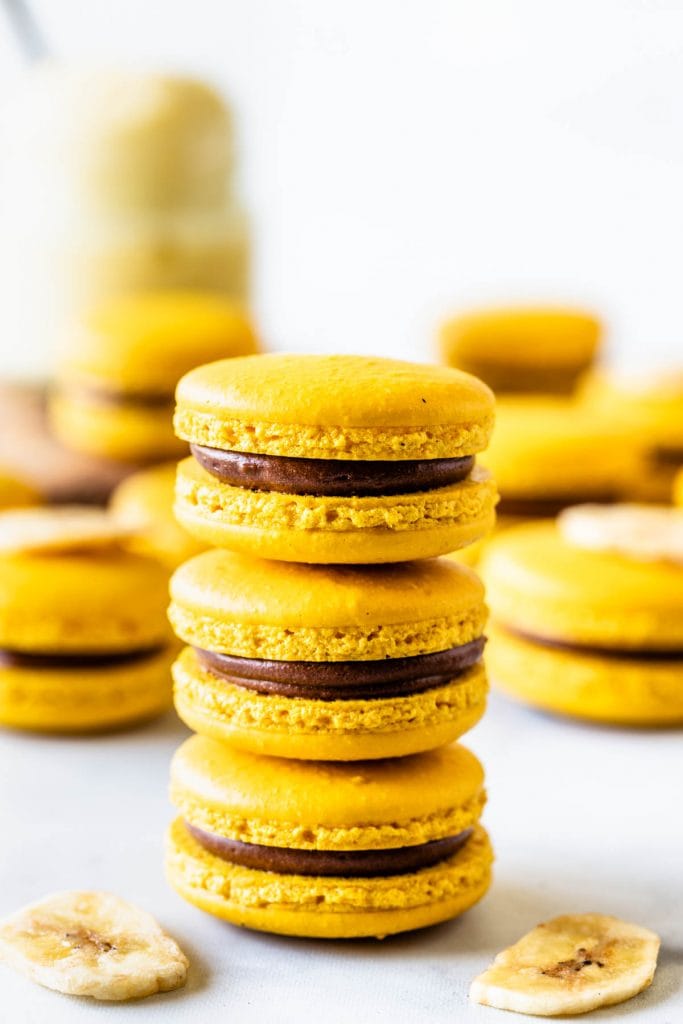 stacked yellow macarons with chocolate filling and a dried banana chip on top