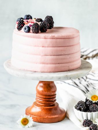 Lemon Blackberry Cake pink cake topped with blackberries and blueberries, on a cake stand