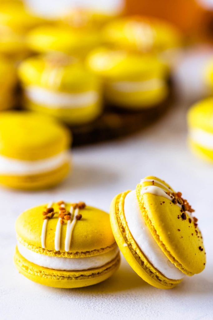 Honey Macarons topped with bee pollen with a jar of honey on the back
