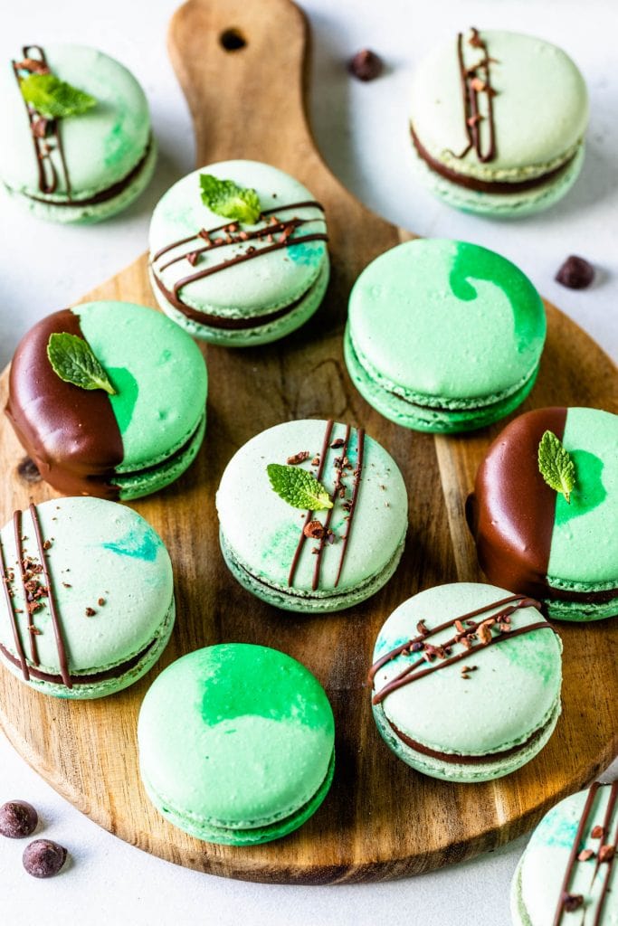 Mint Chocolate Macarons dipped in chocolate filled with ganache on a wooden board