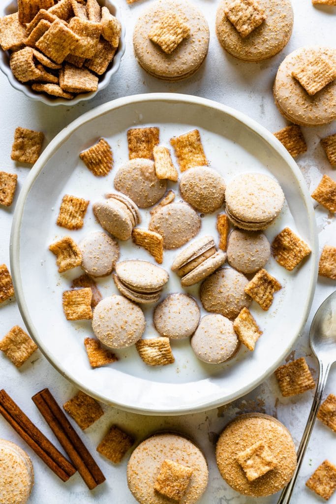 cereal macarons in a bowl with cinnamon toast crunch cereal and milk