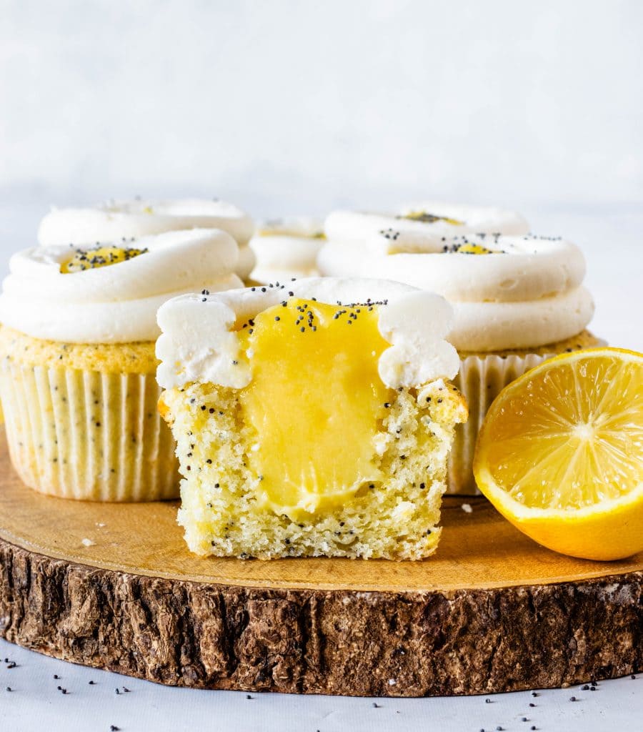lemon poppy seed cupcakes filled with lemon curd cut in half to show the filling of the curd