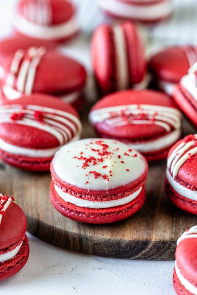vibrant Red Macarons drizzled with white chocolate topped with red velvet cake crumbs