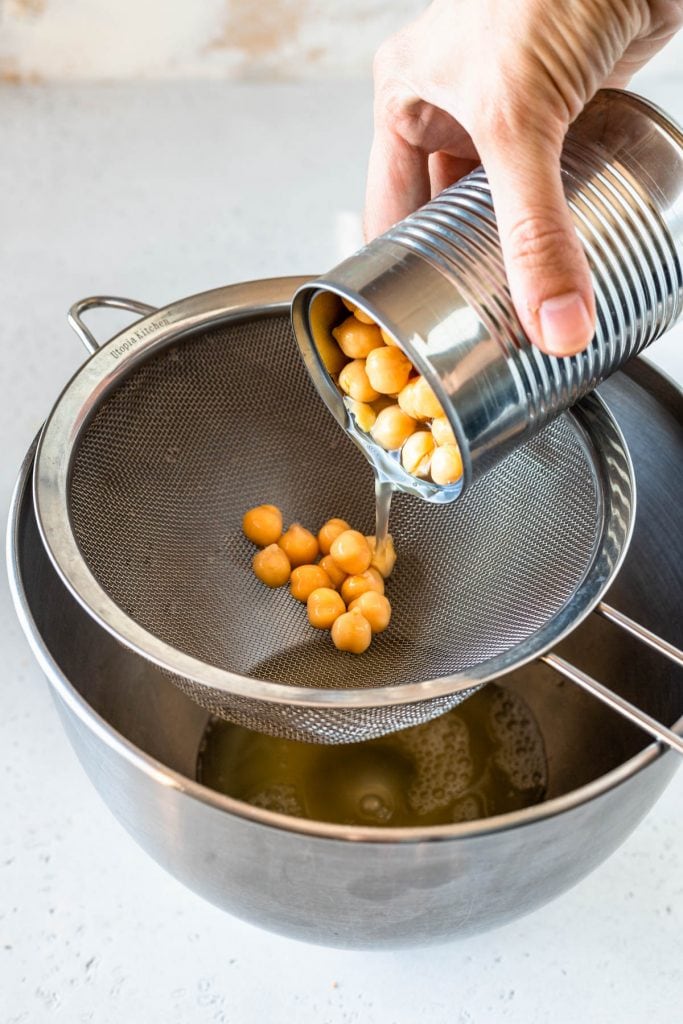 draining a can of chickpeas over a collander