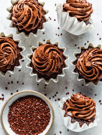 cupcakes with chocolate frosting seen from the top with sprinkles around