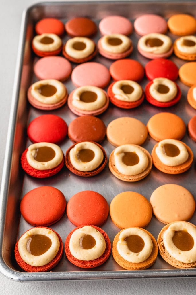macaron shells filled with a dome of buttercream frosting, and caramel sauce in the middle.