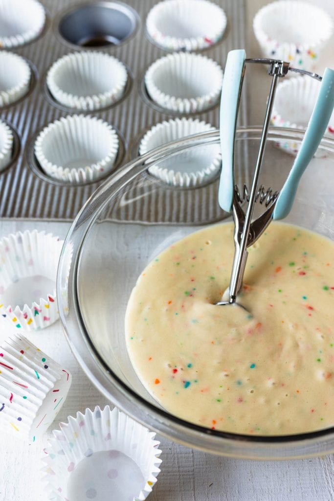 funfetti cupcake batter with cupcake liners and cupcake pan around.