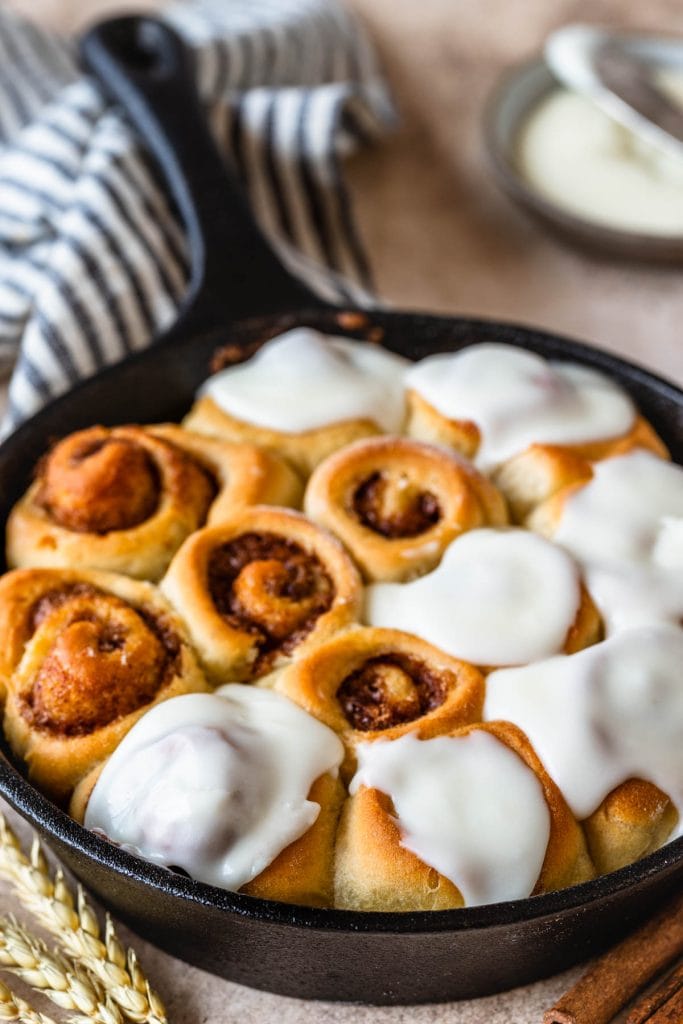 Mini Cinnamon Rolls in a skillet, topped with cream cheese frosting.