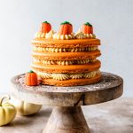 Pumpkin Caramel Macaron Cake topped with pumpkin candy corns on top of a cake stand.