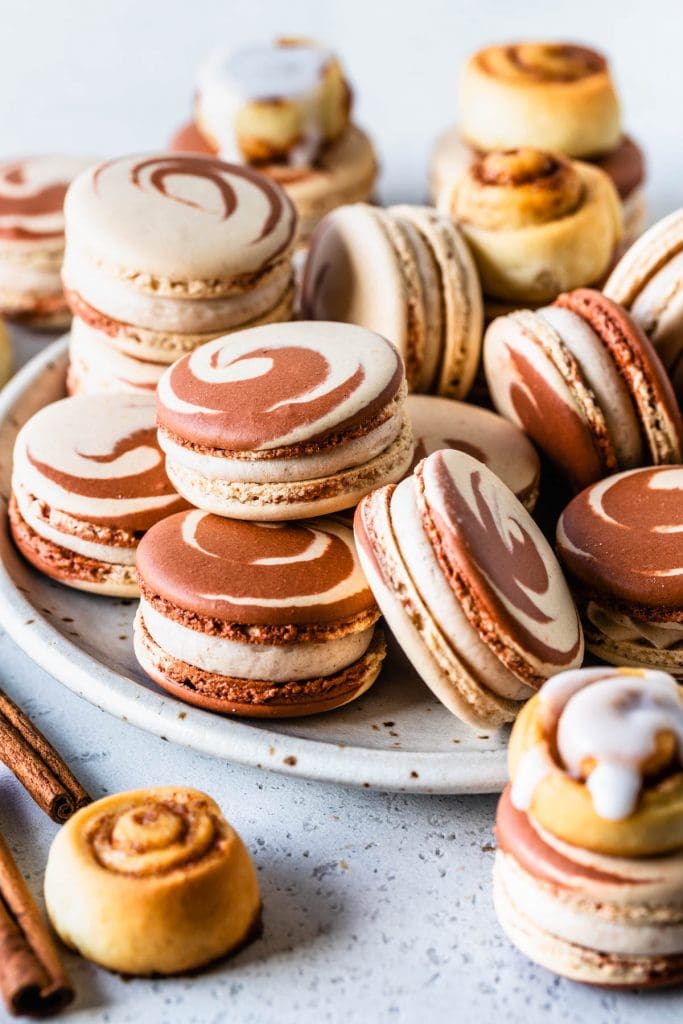 macarons on a plate, with swirl shells, and also topped with mini cinnamon rolls.