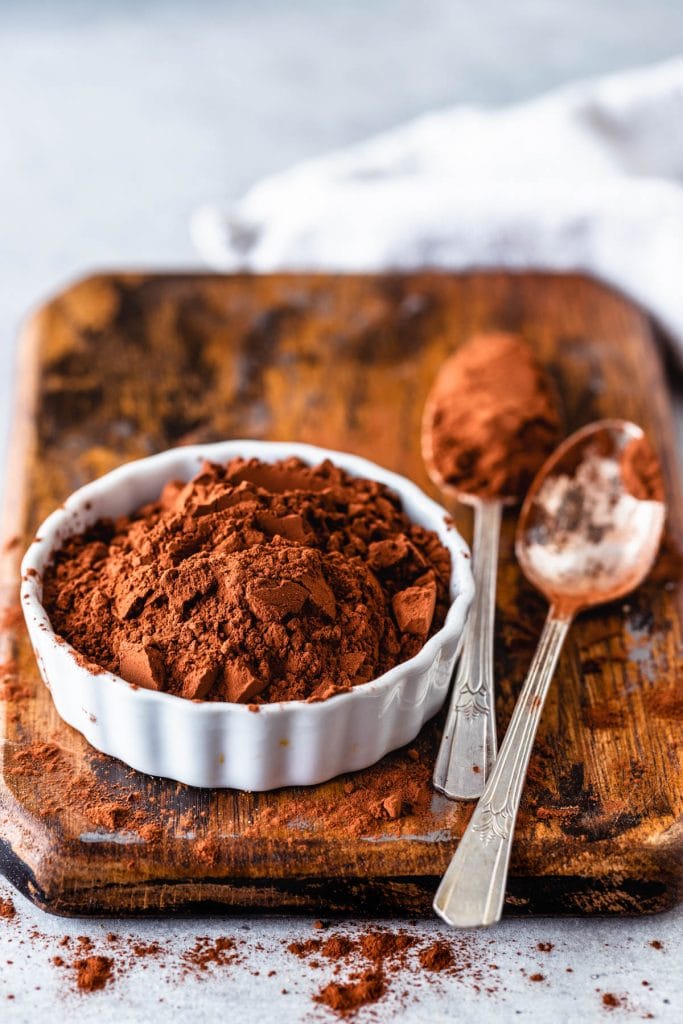 cocoa powder in a small ramekin with two spoons on the side.