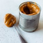 Stove Top Dulce de Leche in a can of condensed milk with a spoon next to it.