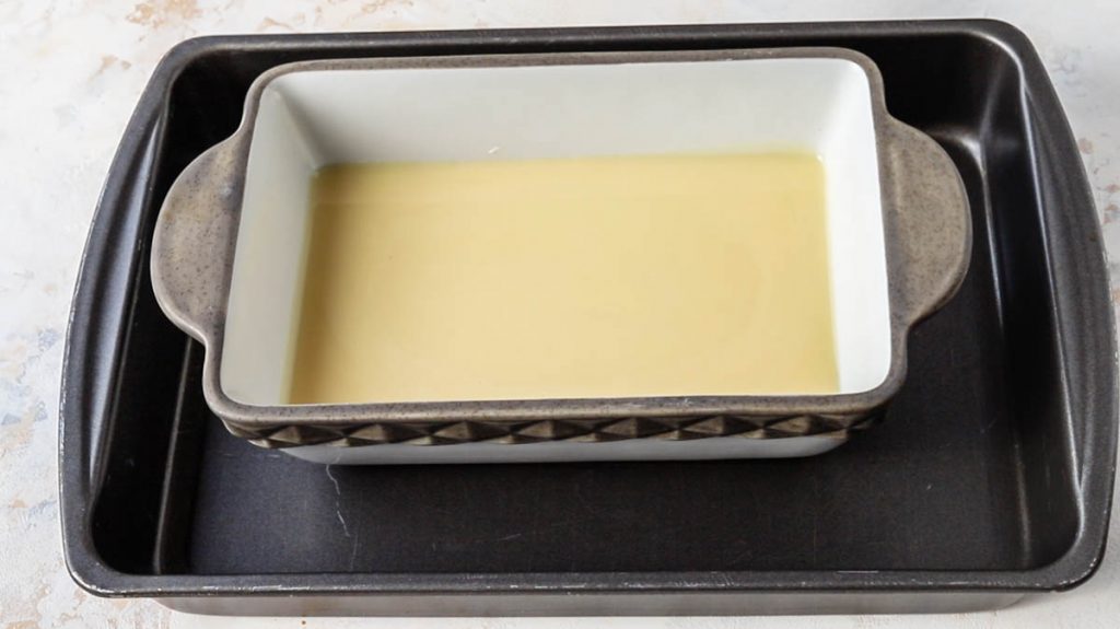 a pan with condensed milk inside of a larger roasting pan.