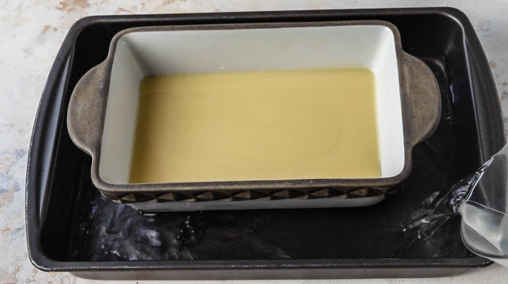 pouring water in a large pan with a smaller pan fitted inside with condensed milk.